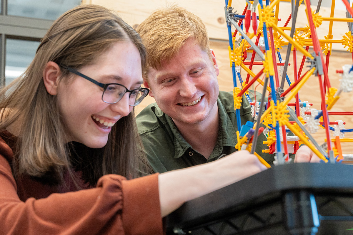Sean Devine works with fellow student to build a ferris wheel to model cyberattacks