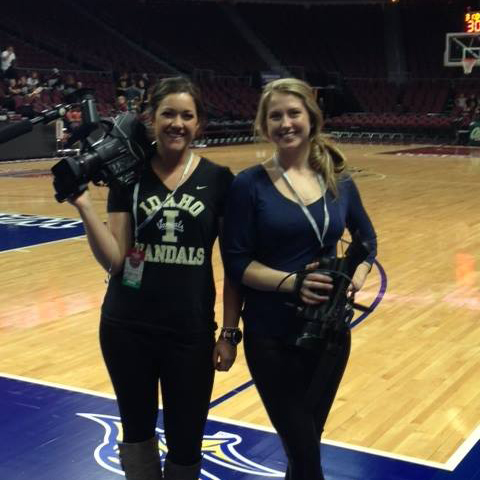 Two students with cameras on the basketball court before a game