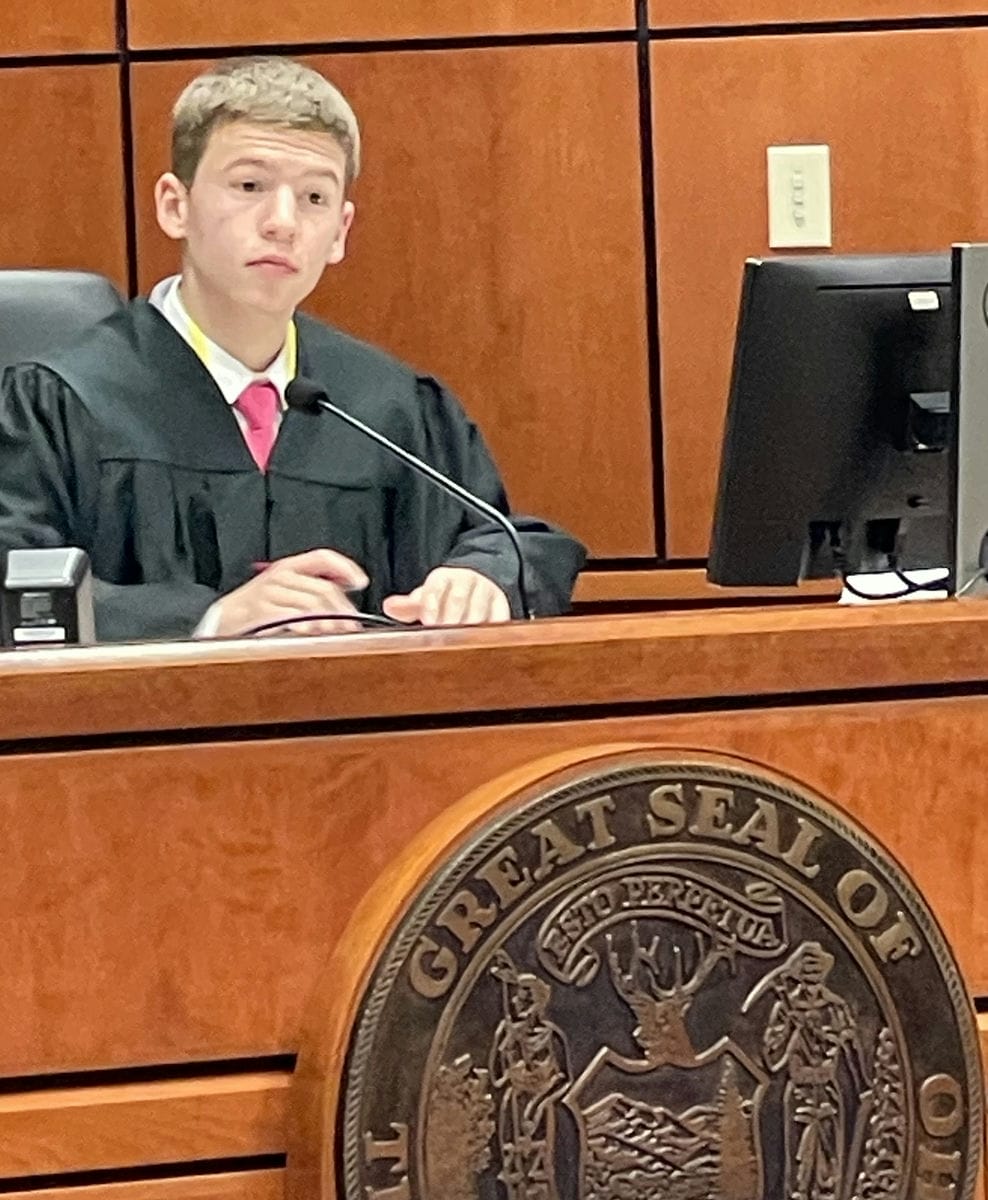 Young boy in judicial attire listens attentively.