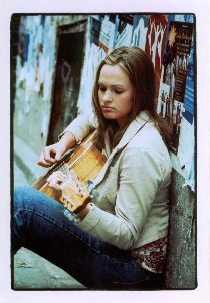 Woman sitting playing guitar.