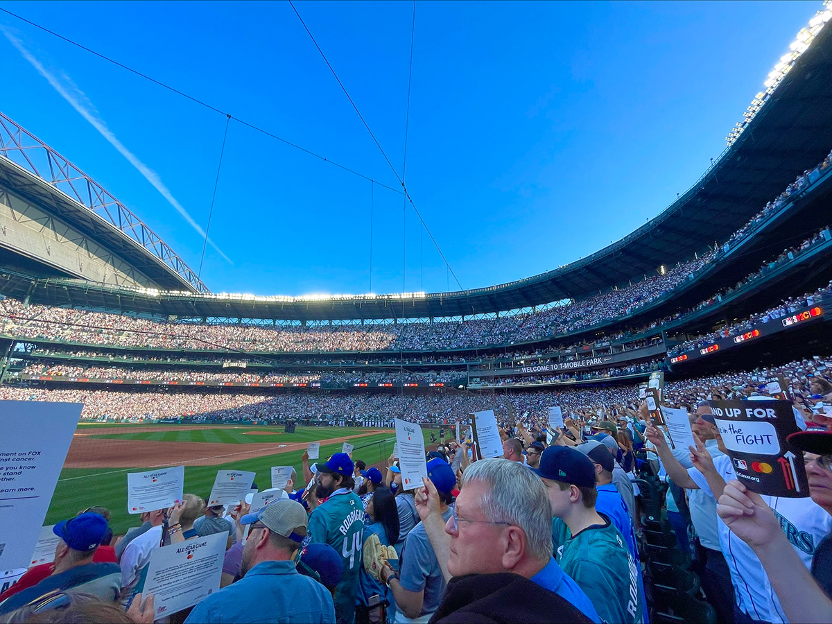 Photo of people standing in baseball stadium holding cards.