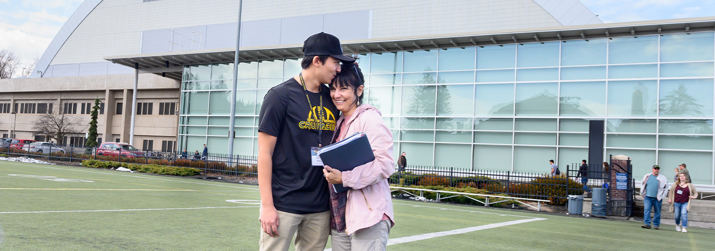 A student hugs his mother outside of the Kibbie Dome