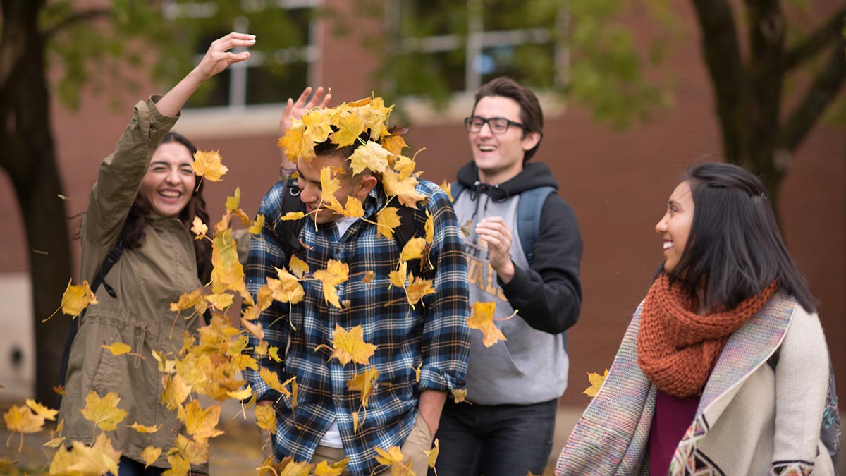 Students throwing fall leaves