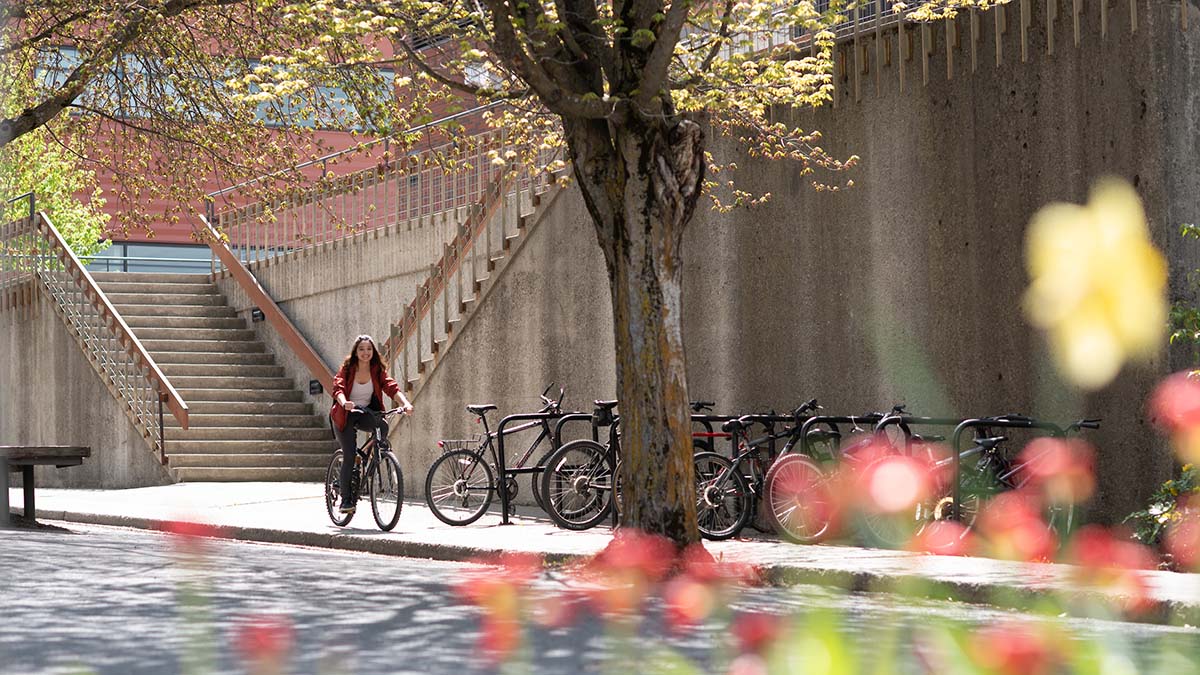 Student riding a bike with spring flowers in foreground