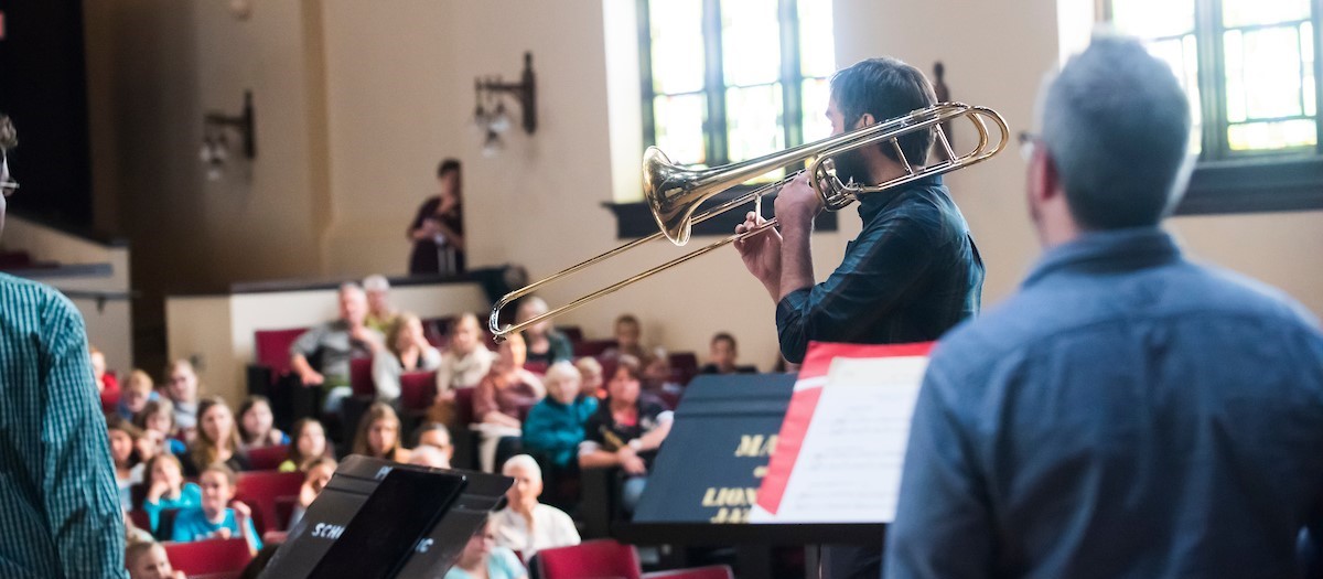 A trombone player performs in a packed Administration Auditorium 