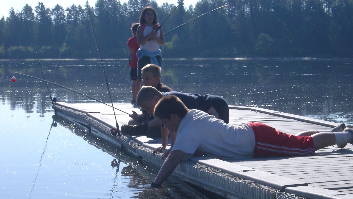 Five children with fishing poles over the water.
