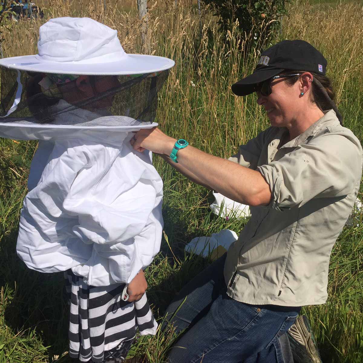 UI Extension educator helping child with beekeeping hood and jacket.