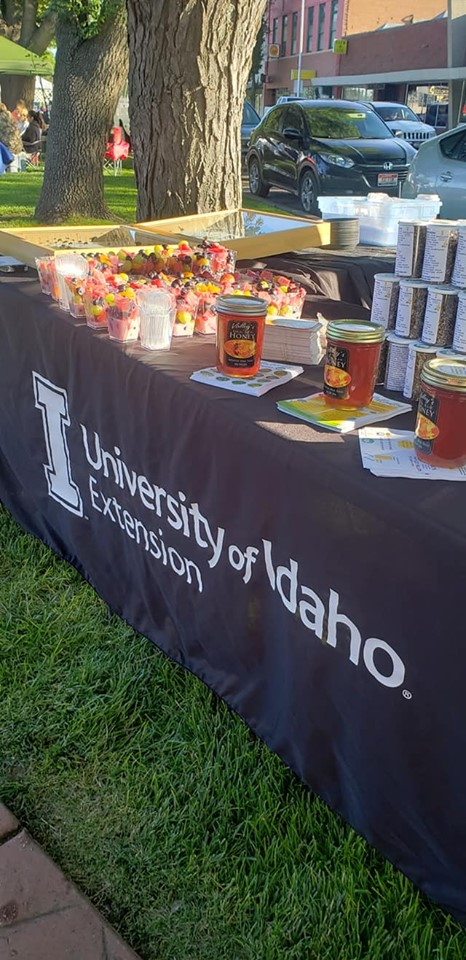 Honey and candies on a table outdoors. The tablecloth says "University of Idaho Extension."