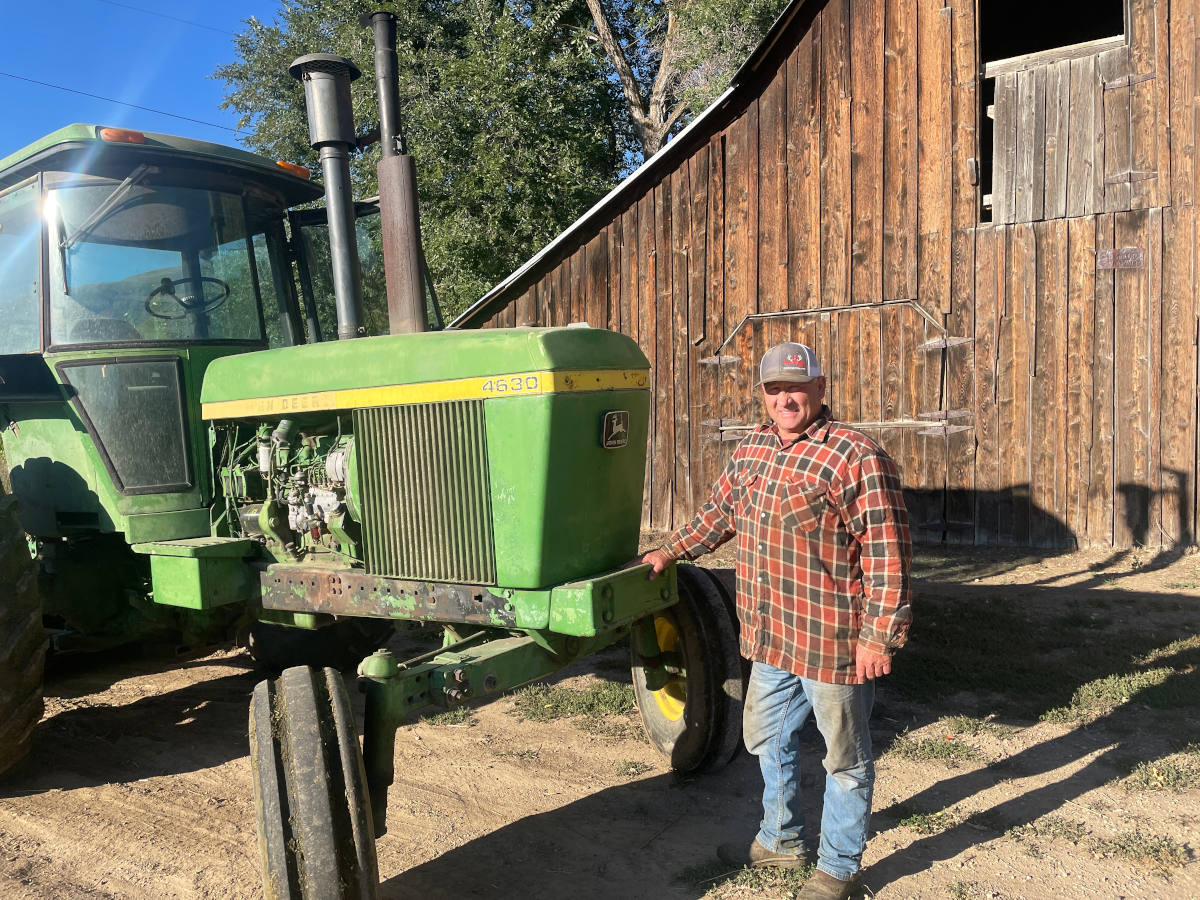 A man stands in front of a tractor on a farm in Idaho.