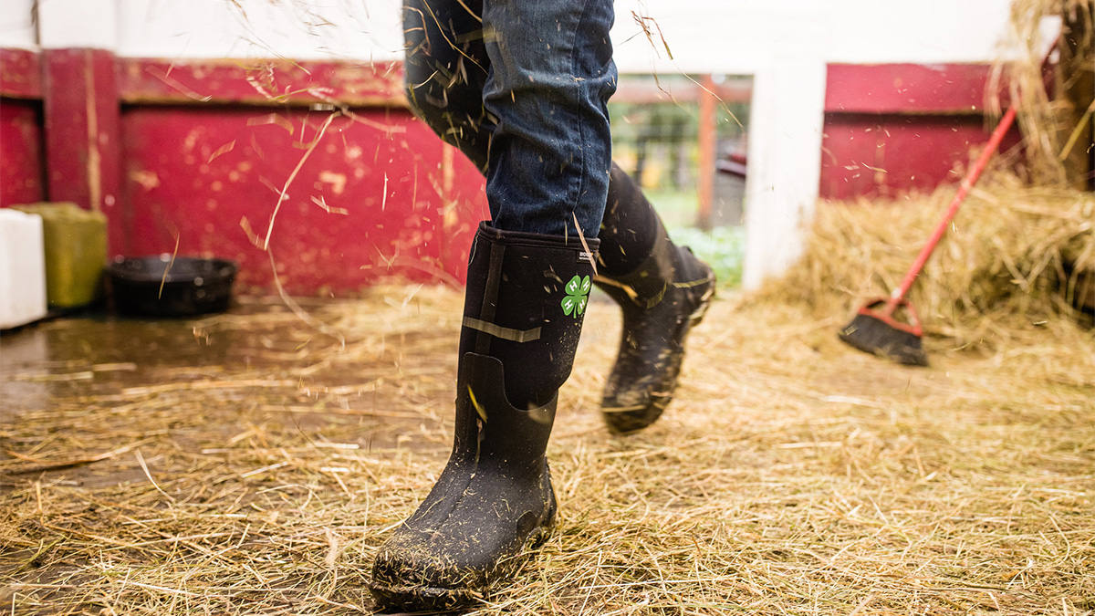 A person wearing boots walking on hay.