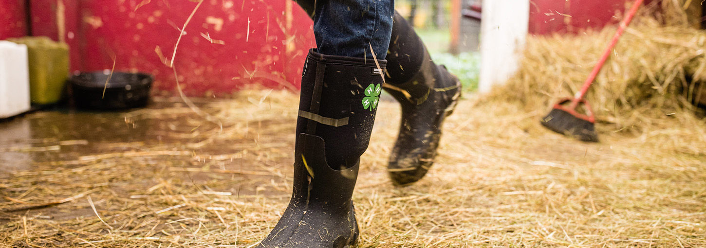 A person wearing boots walking on hay.