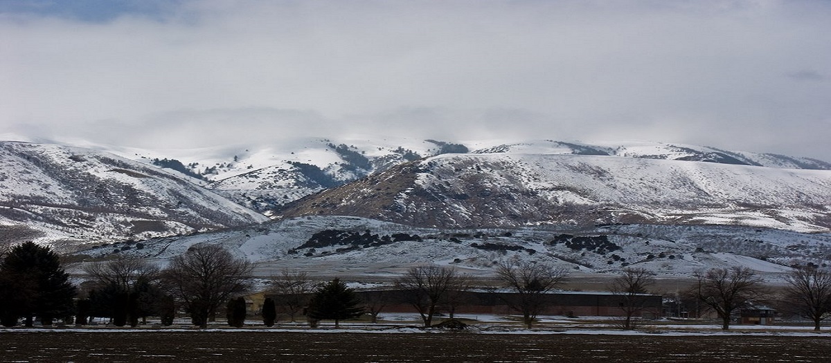 A line of mountains is covered with large patches of snow.