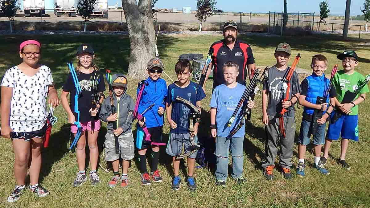 a group of kids with archery equipment