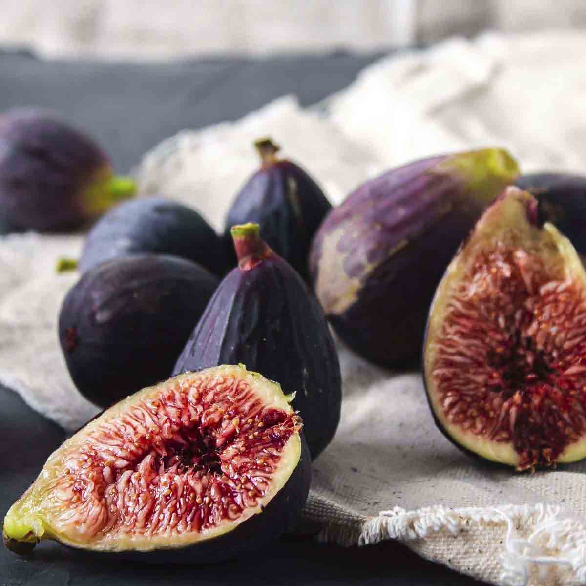 Ripe figs set on table, one cut open.