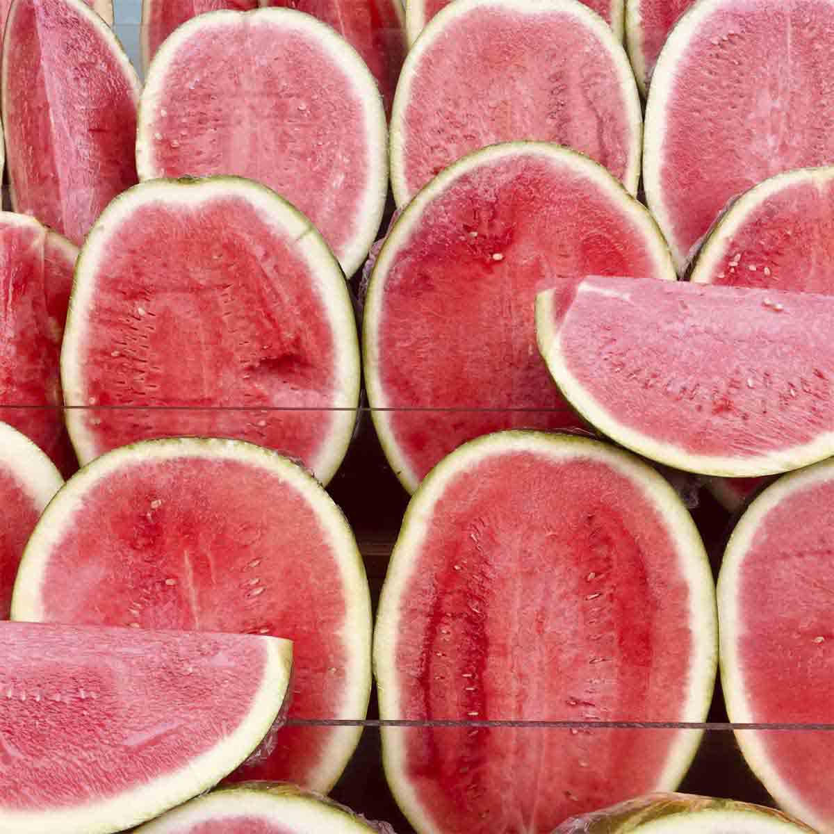 Many ripe watermelon sliced open and on display.