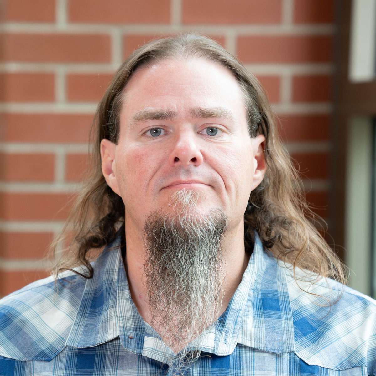 With long hair and a long beard, Dale looks at the camera for a photo.