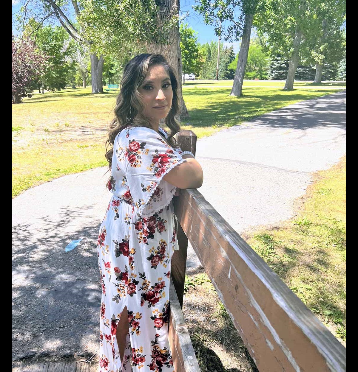 Angelica Gomez stands in front of bushes and trees.