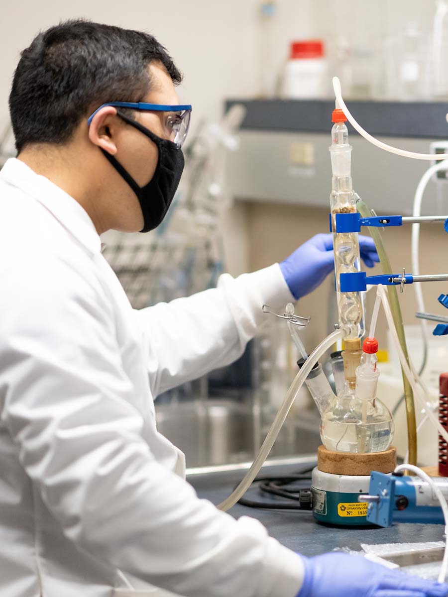 Bishal Thapa stands in a lab next to a plasma reactor, a device that breaks down air and water molecules using electricity.