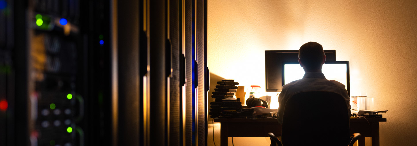 A man stands near a light alongside a giant computer bank.
