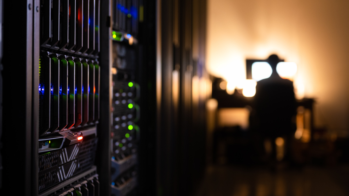 A man stands near a light alongside a giant computer bank.