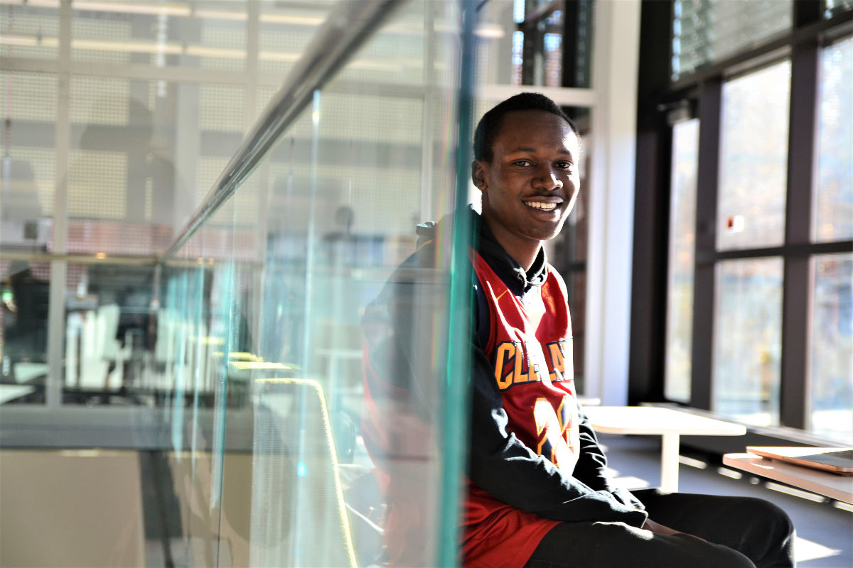 Fredrick Shema sits against a glass wall in the Integrated Research and Innovation Center.