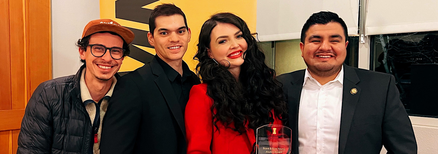 Photo of four people with one holding award.