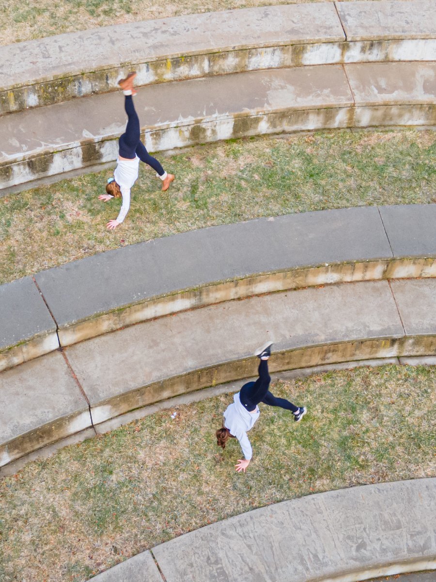 Two dances perform inverted kicks in an outdoor amphitheater.