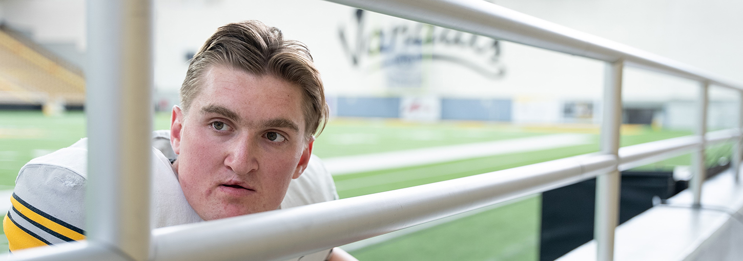 Mathias Bertram wearing Vandal football gear leans against bleacher posts.