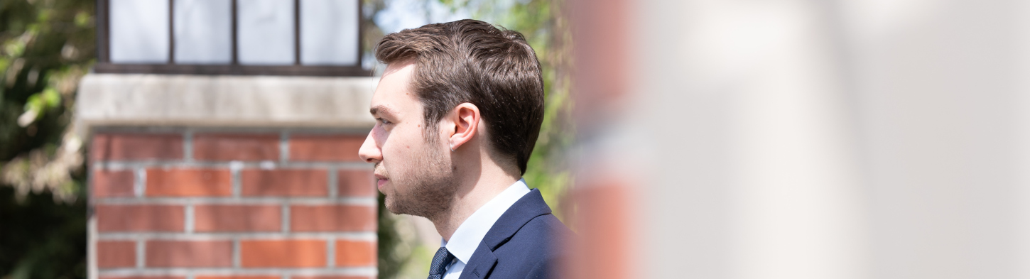 Unshaven man wearing a suit walks past building
