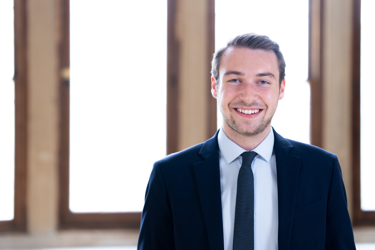 Smiling man wearing blue suit and blue tie and white shirt.
