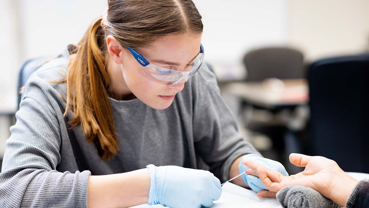 Morgan Flynn takes blood from a person’s finger.