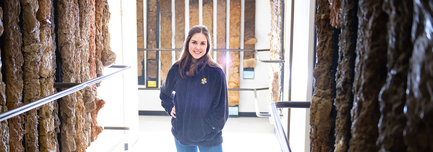 Woman stands in hallway between soil monoliths.