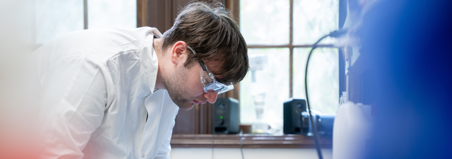 Man wearing lab coat and safety glasses
