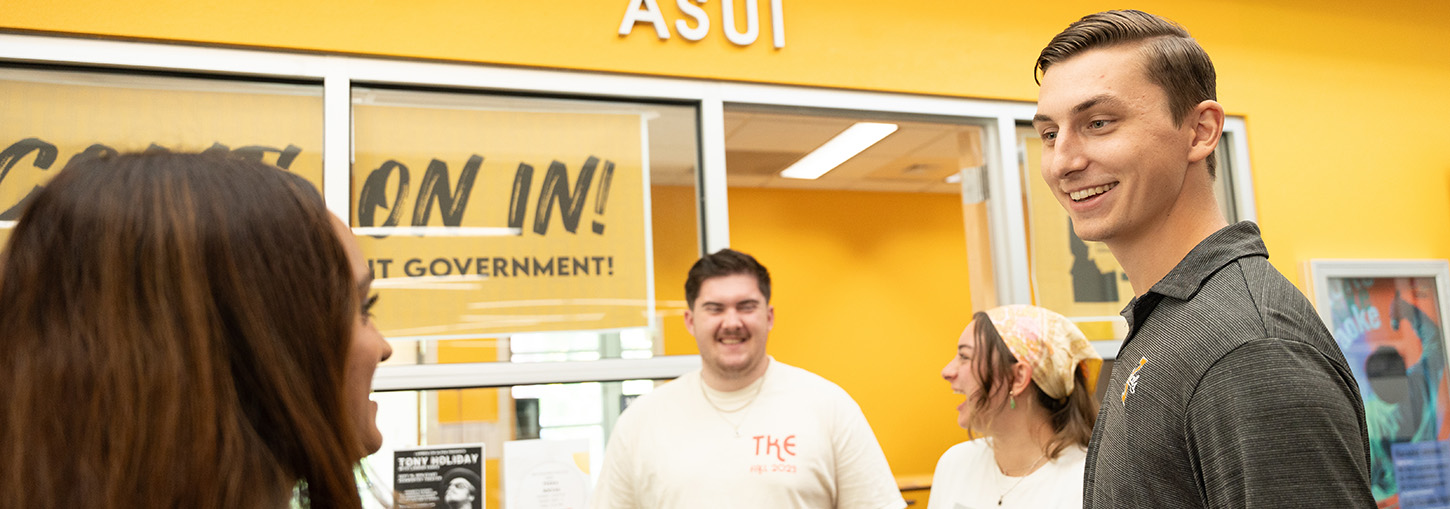 Man among group smiles at a fellow student.
