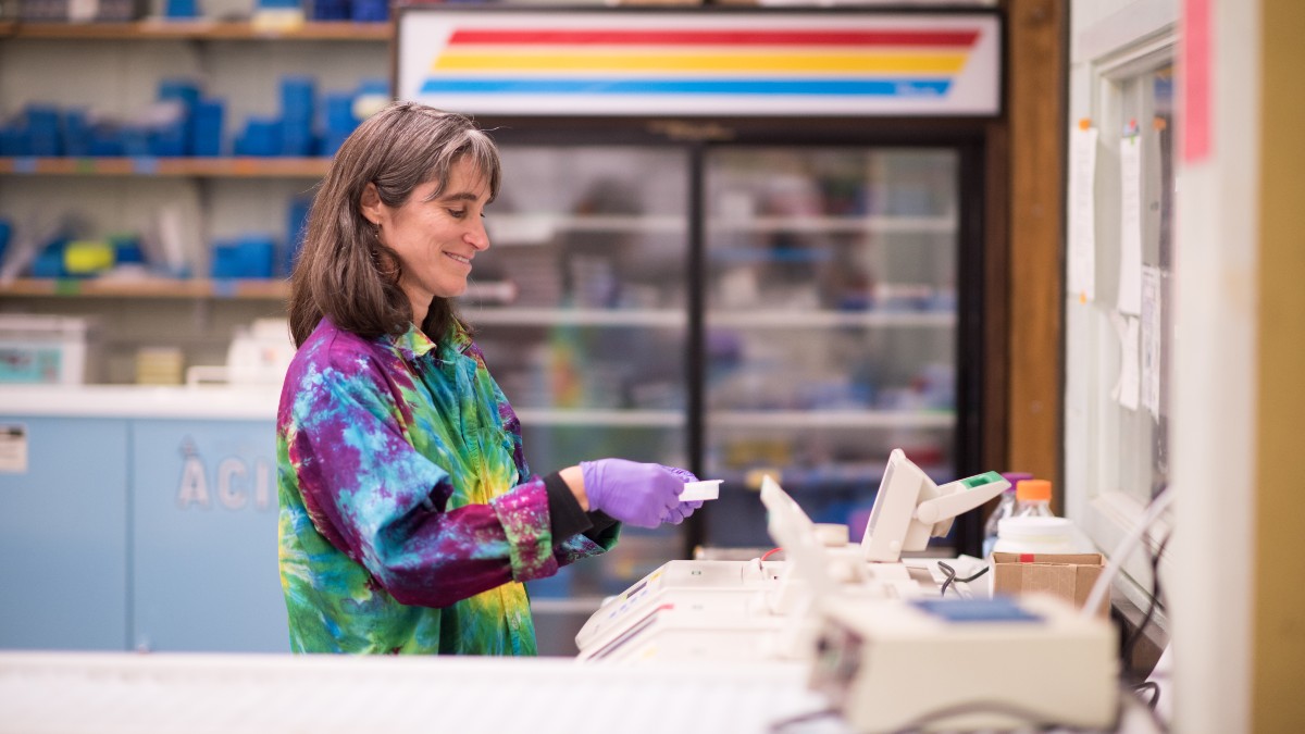 Lisette Waits works in her lab with a tie-dyed lab coat.