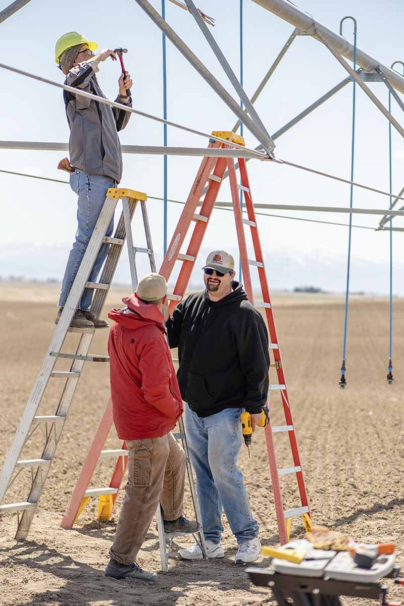 Clarence Robison, Kevin Kruger and Erin Brooks work to install crop sensors on the Mid-Elevation Sprinkler Application (MESA) pivot system at the Idaho CAFE research farm.