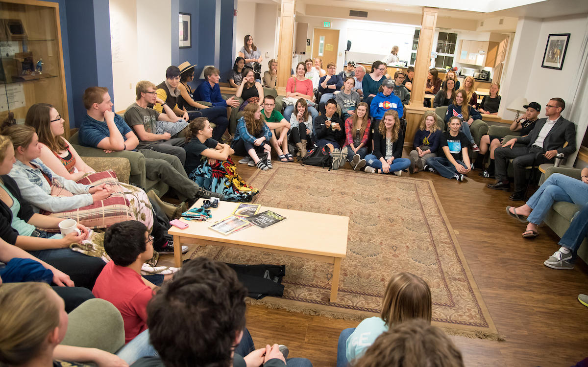 Students sit in a circle in a common area of Scholars LLC while a professor leads a fireside chat