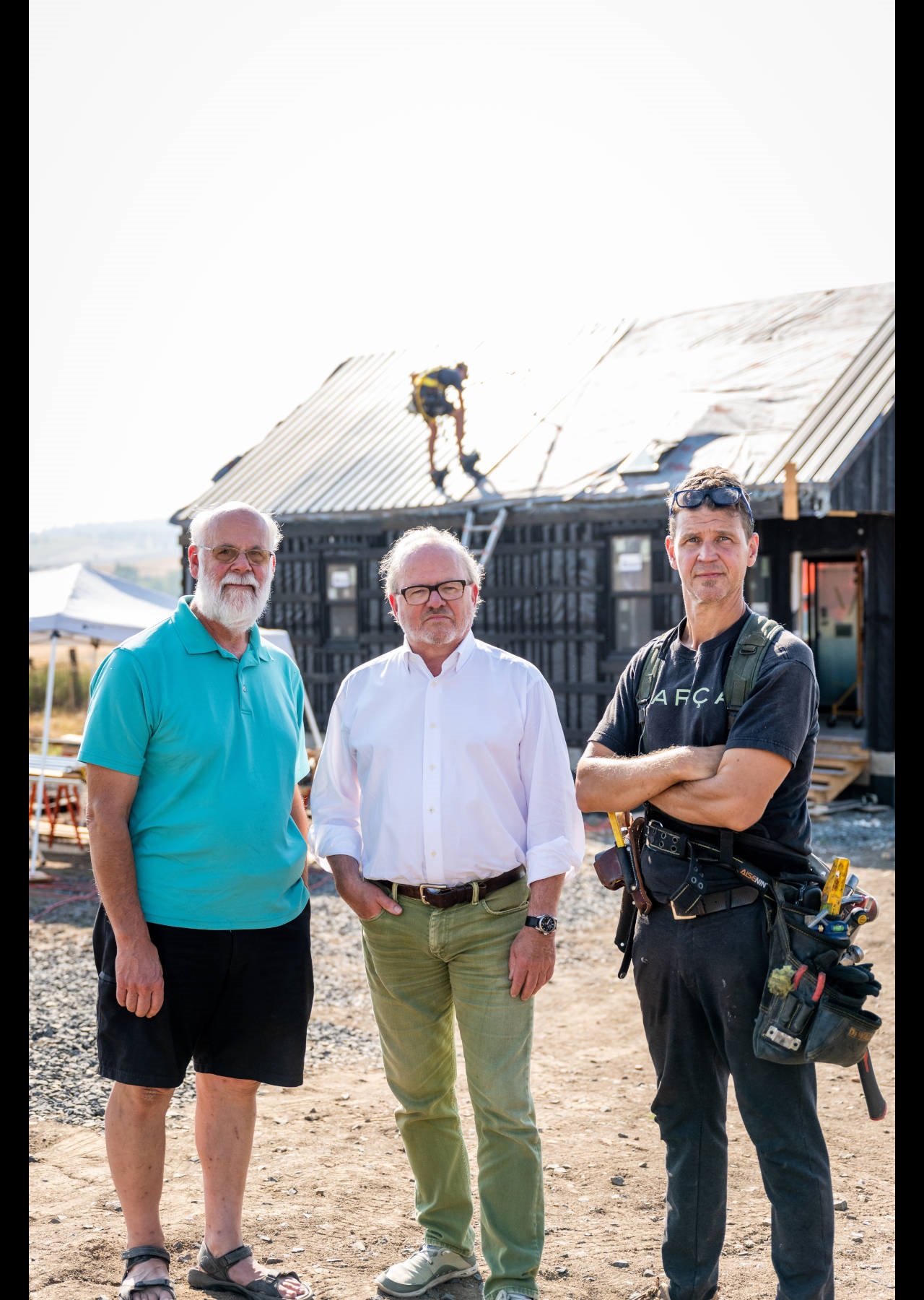 Three people standing in front of house construction.