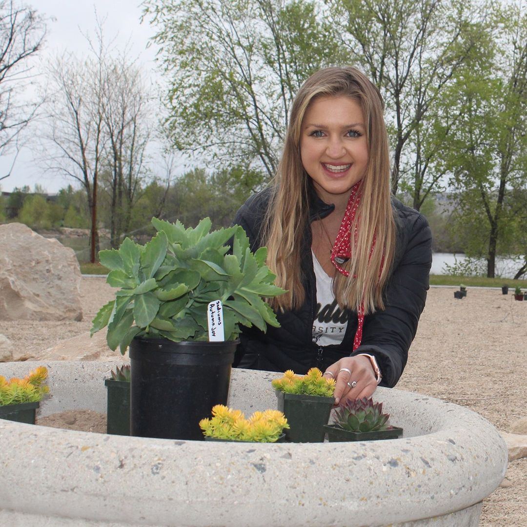 Olivia Harman poses with plants that were added to the fire-wise landscape demonstration garden.
