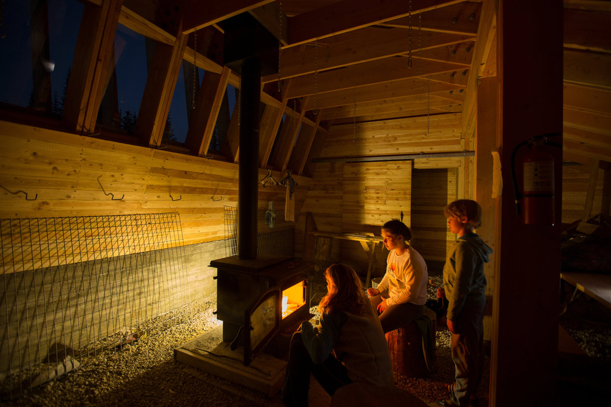 People warming themselves by the fire inside the Moose Creek Warming Hut