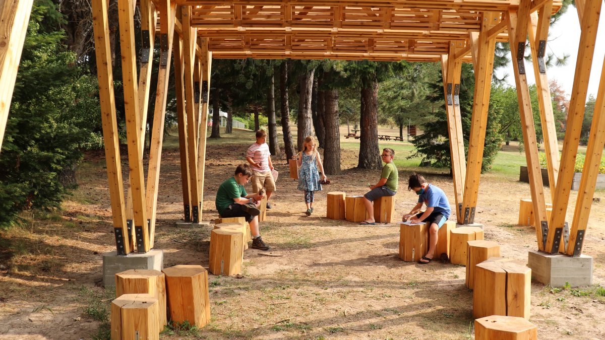 McDonald students sit on stumps in their new wooden outdoor classroom.