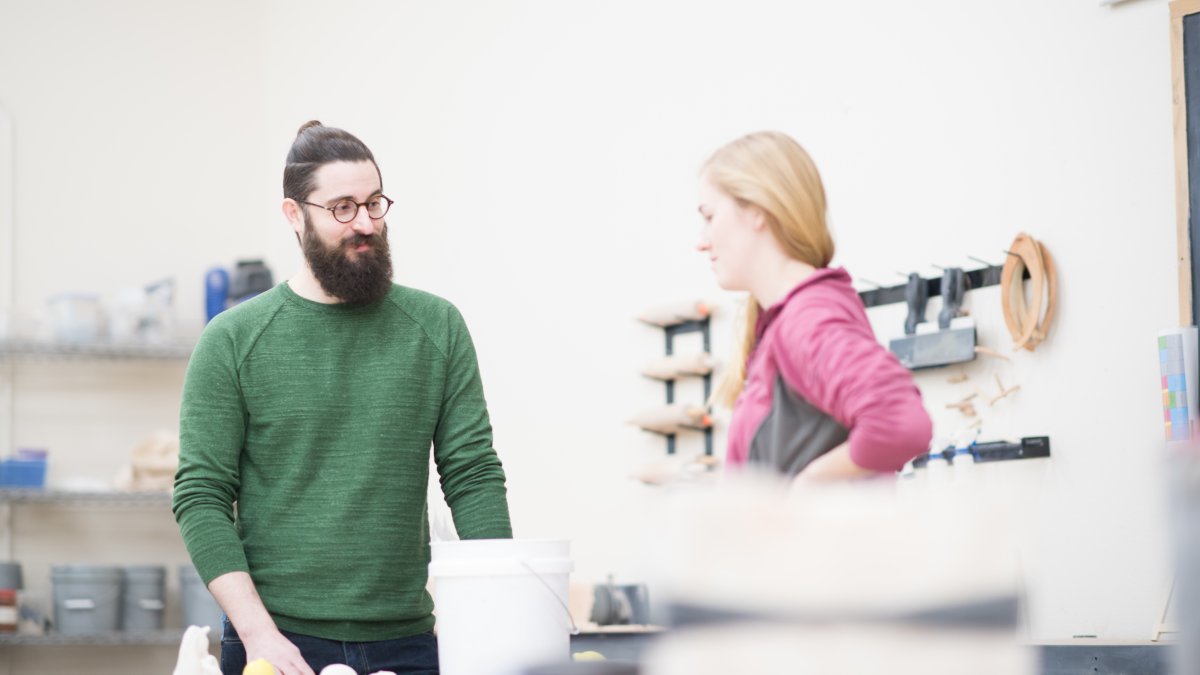 Casey Doyle talks with a student in a design studio.