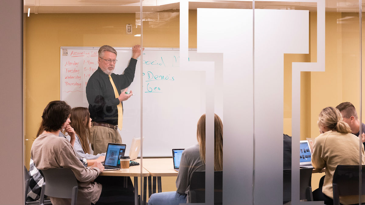 Mike McCullough, professor in the Marketing department, leads a study session in a remodeled conference room in the Albertson building basement. 