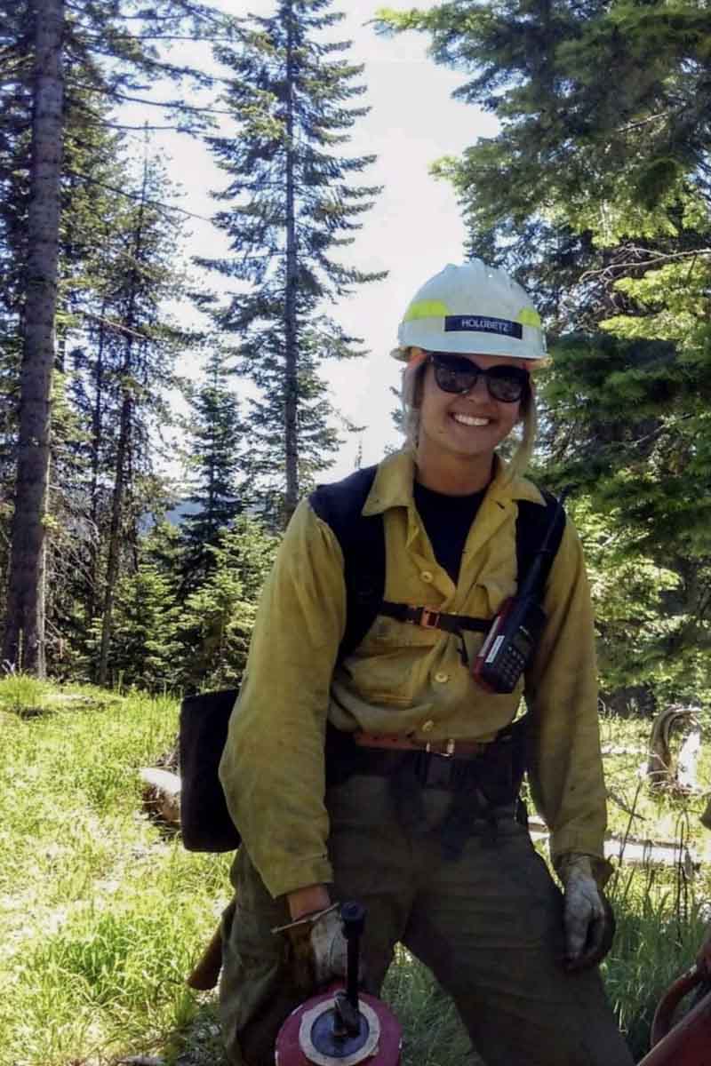 A woman wildland firefighter poses in the forest