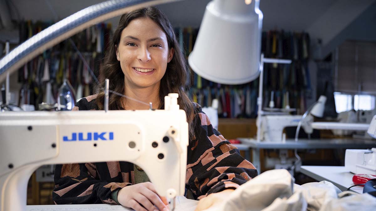A woman sits behind a sewing machine.