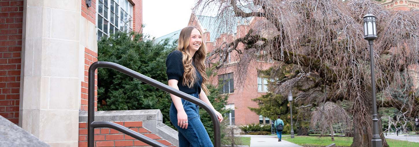 A woman walks down a set of steps outside a building on the University of Idaho campus.