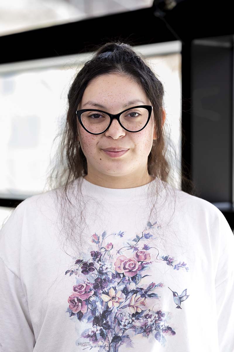 A head and shoulders photo of a woman with long dark hair wearing glasses.