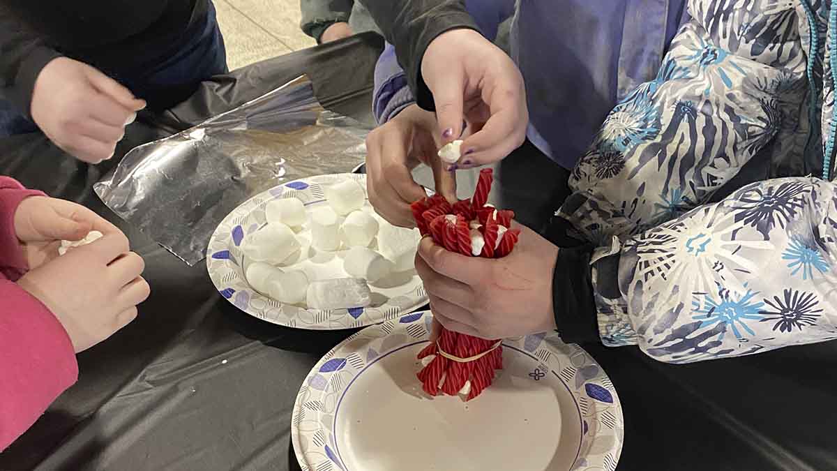 Youth holding twizzlers and marshmallows on a plate.