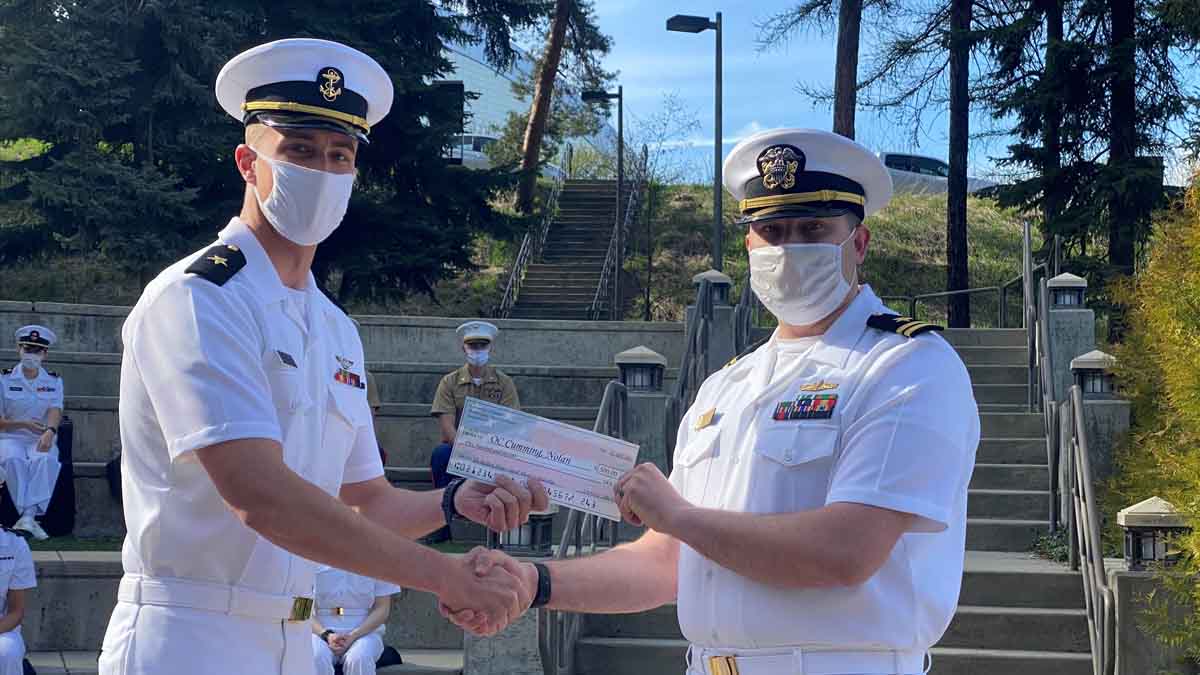 Two men in naval dress shake hands.
