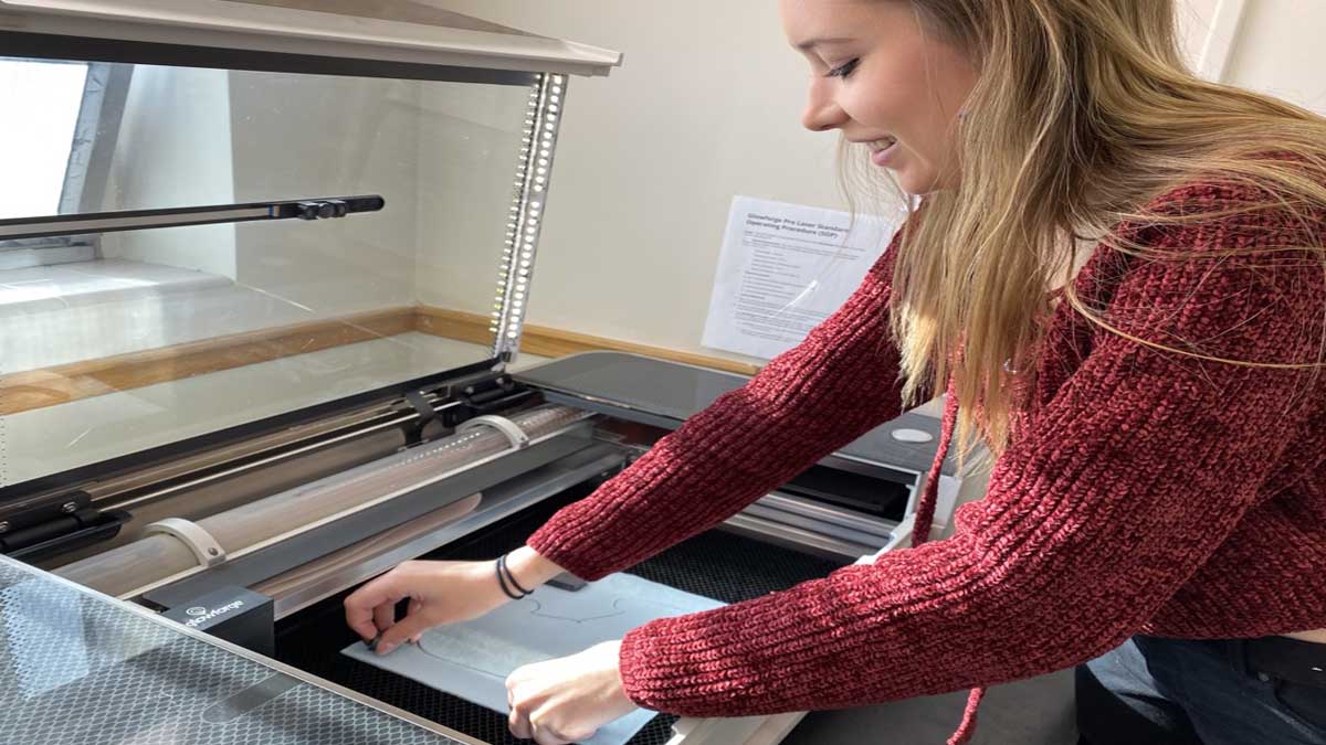 Student Meghan White removing a project from the laser cutter.